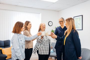 Five ladies in a circle with cups of tea in a clinic room