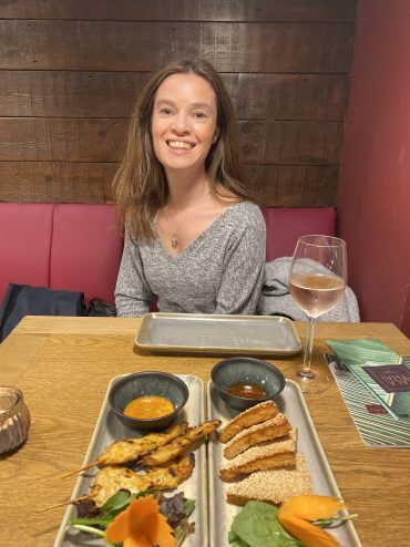 Emma Mills in a restaurant with food and wine on the table in front