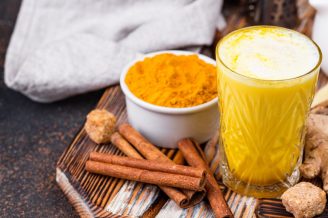 Turmeric latte, cinnamon sticks, and ginger on a wooden board